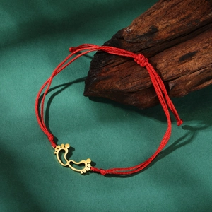 Red braided rope bracelet with golden hollow footprint pendant and adjustable sliding knot