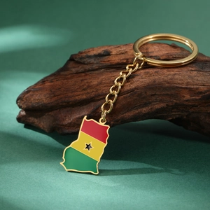 Detailed close-up of a golden Ghana map keychain with colorful enamel flag on wood texture