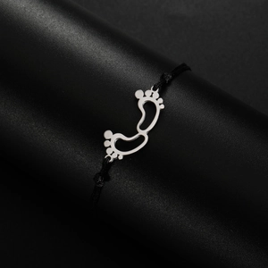 Close-up of baby footprint charm with silver finish on minimalist black braided cord