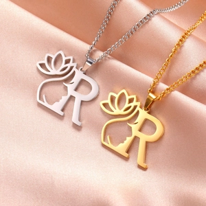 Détails du collier lettre R avec lotus doré et argenté sur un tissu en soie