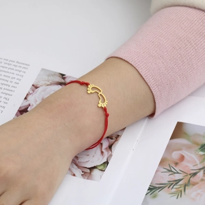 Detailed close-up of a red woven bracelet with adjustable knots and golden baby feet charms
