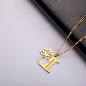 Gros plan du pendentif lettre I doré avec silhouette de femme et lotus sur cuir noir