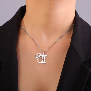Détail du collier argenté avec initiale I, pendentif lotus et visage sur un mannequin