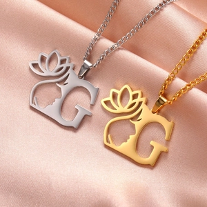 Détail des colliers G en or et argent avec motif de lotus sur un tissu en soie rose
