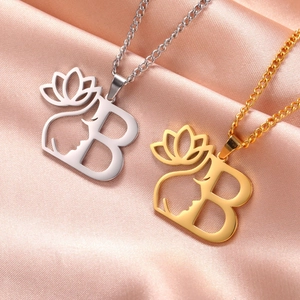 Détail du collier en acier inoxydable avec lettre B, fleur de lotus et profil de femme.