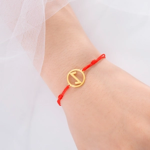 Makroansicht des verstellbaren roten Kordelarmbands mit goldenem Runen-Anhänger