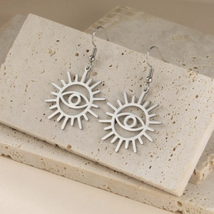 Silver evil eye moon knight drop earrings hanging on a natural beige stone display