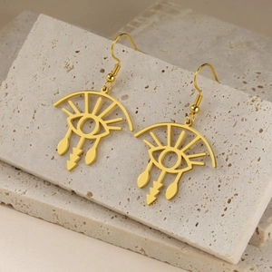 Artistic golden evil eye eyelashes drop earrings displayed on marble stone background