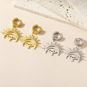 Macro view of boho style stainless steel sun and eye pendant earrings in gold and silver