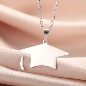 Silver stainless steel graduation cap pendant necklace on soft pink satin background