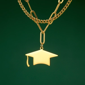 Macro detail of golden double-layer necklace with polished graduation cap pendant