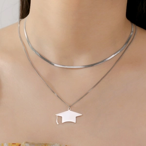 Detailed view of layered stainless steel necklace with a graduation cap pendant on neck