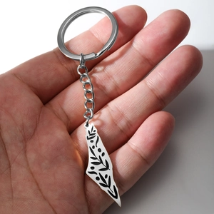 Polished Israel map keychain with black leaf patterns held in hand for scale
