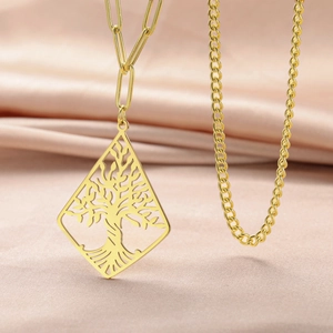 Detailed shot of golden Tree of Life pendant on paperclip chain over silk fabric