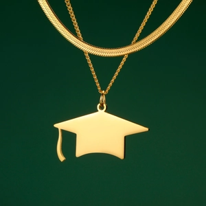 Close-up of golden graduation cap pendant and layered flat snake chain necklace