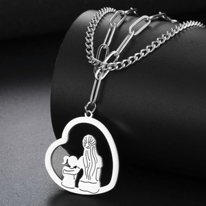 Makroaufnahme von Herzanhänger mit Mutter-Tochter-Silhouette an einer Büroklammerkette