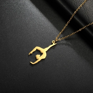 Detailed close-up of a golden rhythmic gymnast pendant on a textured black surface