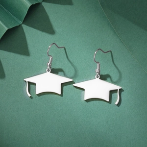 Détail de boucles d'oreilles diplômé en argent avec émail blanc sur fond vert foncé