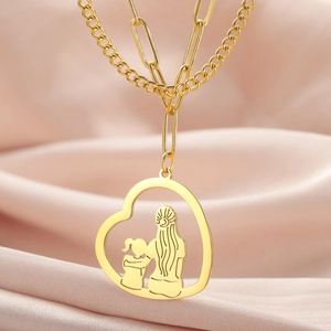 Detail einer goldenen Doppelkette mit Herzanhänger und Mutter-Kind-Umarmung als Motiv