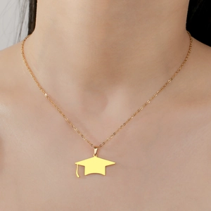 Polished gold graduation cap pendant necklace worn by a model in a close-up detail shot