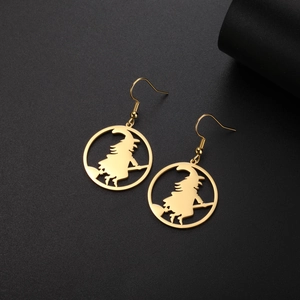 Detailed close-up of golden witch on broom silhouette earrings in a stainless steel ring