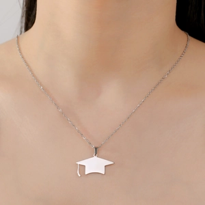 Detail view of a polished stainless steel graduation cap pendant necklace worn on neck