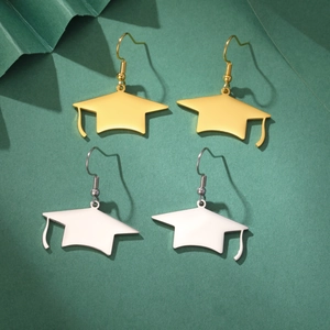 Détail de boucles d'oreilles en forme de toque en or et argent sur fond vert foncé