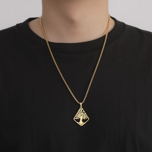 Close-up of a gold tree of life pendant on a round box chain worn by a male model