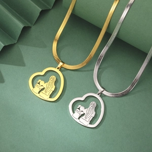 Detail von Gold- und Silber-Herzanhängern mit Mutter-Kind-Silhouette auf grünem Papier