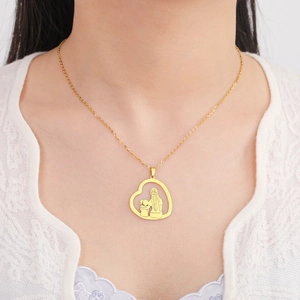 Detail der goldenen Herzanhänger-Halskette mit Mutter-Kind-Motiv an einem Model