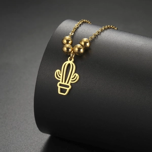 Detailed macro view of golden hollow cactus pendant and polished beads on stainless chain