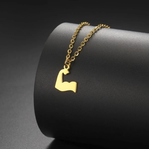 Dettaglio macro di una collana con ciondolo muscolo d'oro su un espositore nero opaco