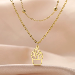 Close-up of golden layered necklace with succulent plant pendant on silk fabric