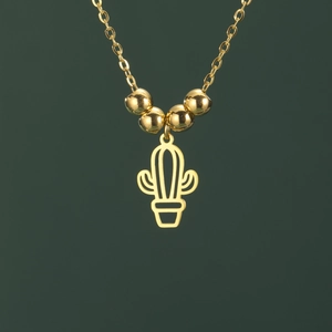 Detail view of a gold-plated hollow cactus pendant necklace on a dark green background