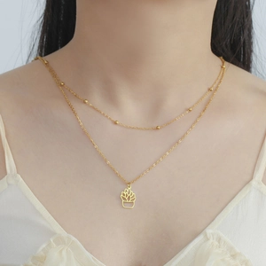 Detail of a gold double-layer necklace featuring a cutout succulent plant pendant