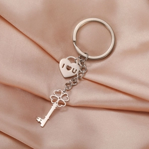Stainless steel four-leaf clover key and heart lock pendant keychain on satin background