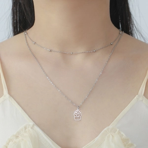 Detail of a layered stainless steel necklace with a hollow succulent plant pendant