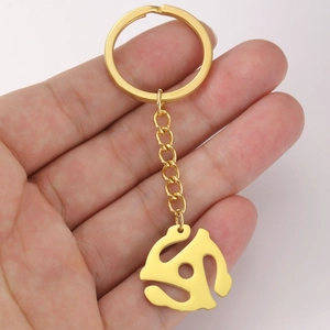 Golden 45 RPM vinyl record adapter keychain made of polished stainless steel on a hand