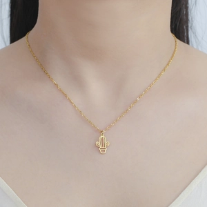 Detail of a minimalist gold cactus pendant necklace on a model's neck for elegant wear