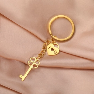Close-up of golden four-leaf clover key and heart lock pendant on champagne satin