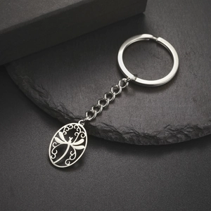 Detailed macro shot of a stainless steel dragonfly pendant keychain on black stone