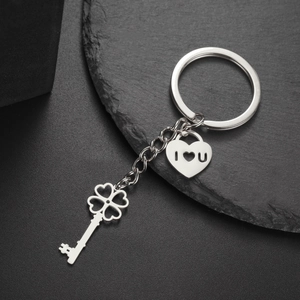 Macro detail of stainless steel heart pendant and clover key ring on dark stone