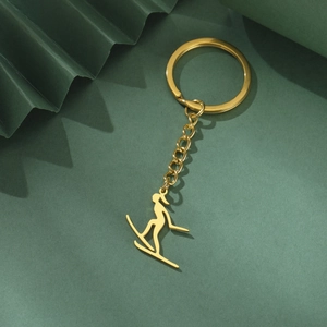 Vue détaillée d'un porte-clés silhouette de skieur doré sur un fond vert texturé
