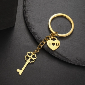 Macro shot of polished gold clover key and heart lock pendant on stainless steel keychain