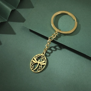 Detailed view of a golden stainless steel keychain with a dragonfly oval pendant