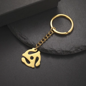 Macro shot of a golden 45 RPM spider adapter keychain on a sleek black stone display