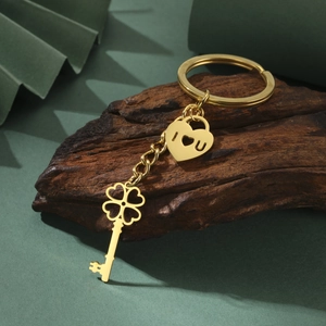 Golden stainless steel four-leaf clover key and heart lock pendant on a dark wood background