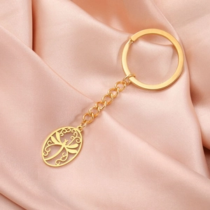 Macro view of gold stainless steel dragonfly pendant with chain and keyring on silk