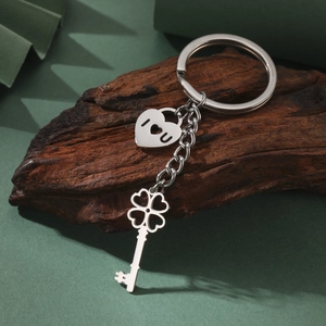 Macro view of stainless steel clover key and heart locket pendant on rustic wood