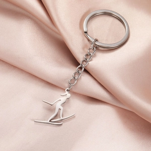 Porte-clés skieur en argent poli posé sur un tissu élégant en satin rose brillant